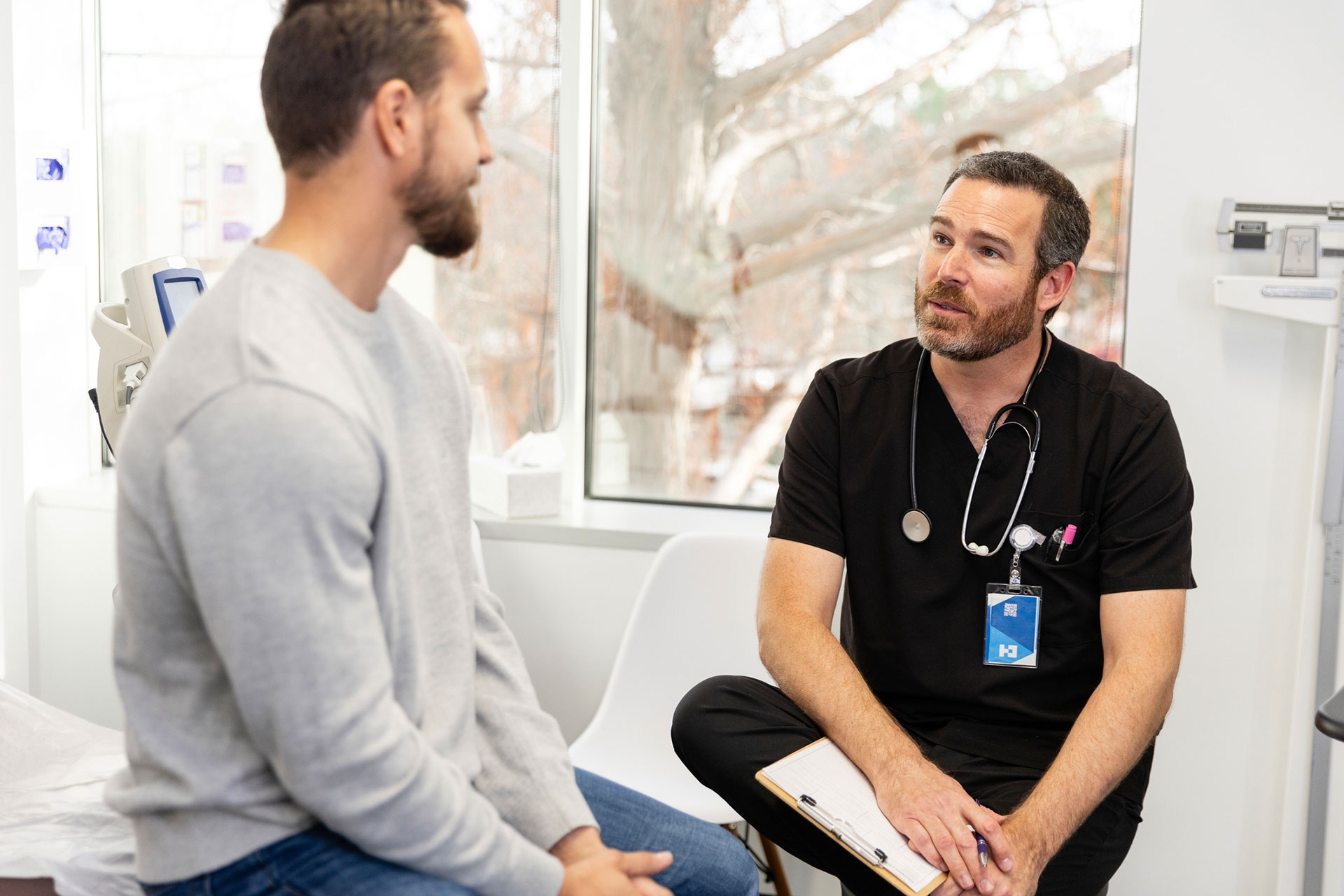 Männlicher Arzt im Anamnesegespräch mit einem Patienten in der Praxis.