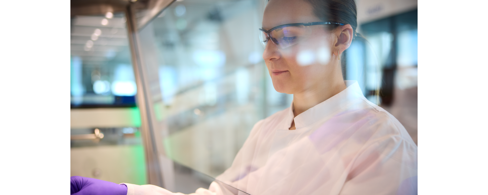 A lab technician wearing goggles operating under the fume hood