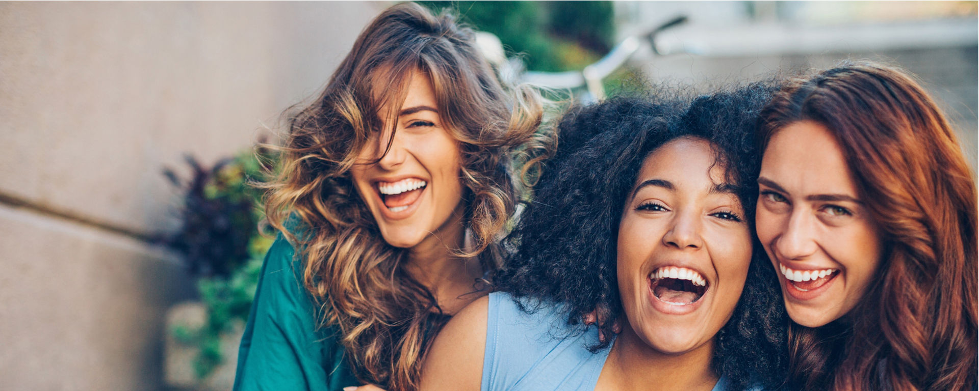 Three young women laughing outdoors