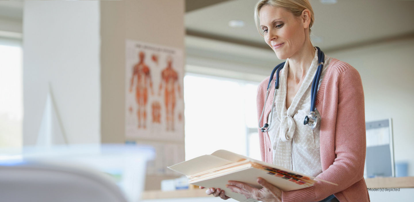 A doctor looking down and reading a medical file