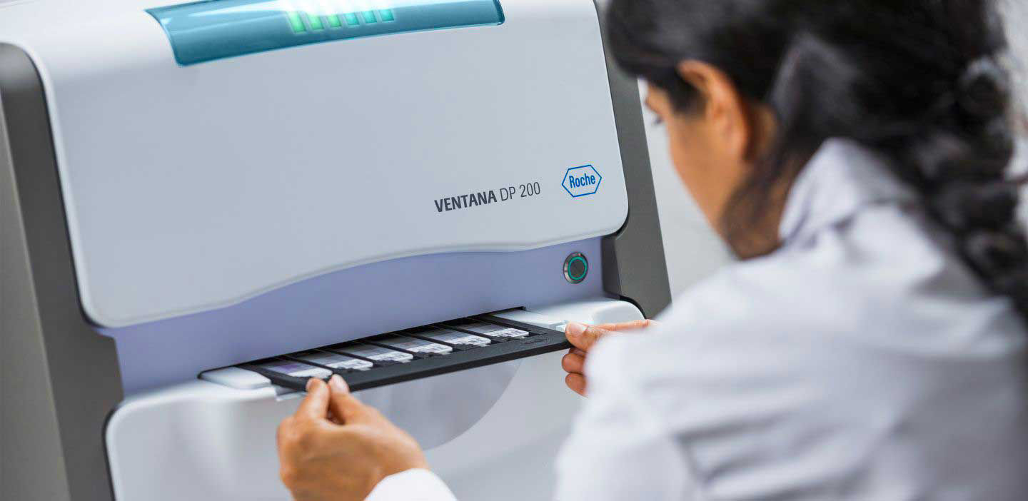 A pathologist pulling out The VENTANA DP 200 digital pathology slide scanner tray