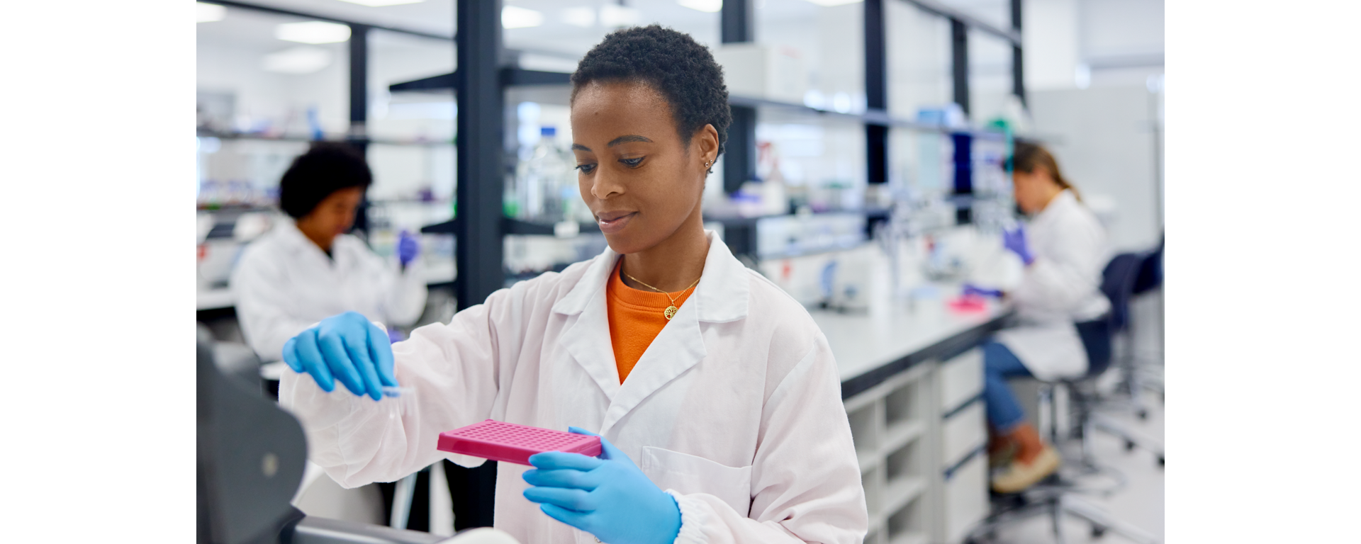 A researcher holds a microwell plate and reagent tubes to carry out RNA library prep with Roche