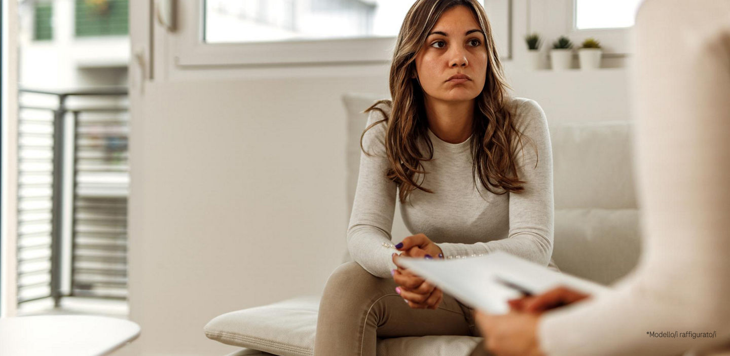 A young unhappy woman, not feeling well, sitting on the sofa, geting a consultation from doctor. 