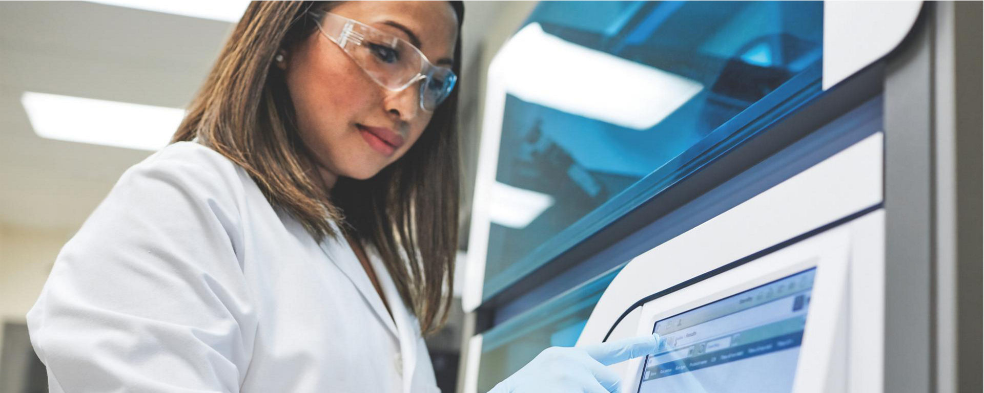 Scientist working with MagNA Pure on a lab-wearing a lab coat and medical gloves