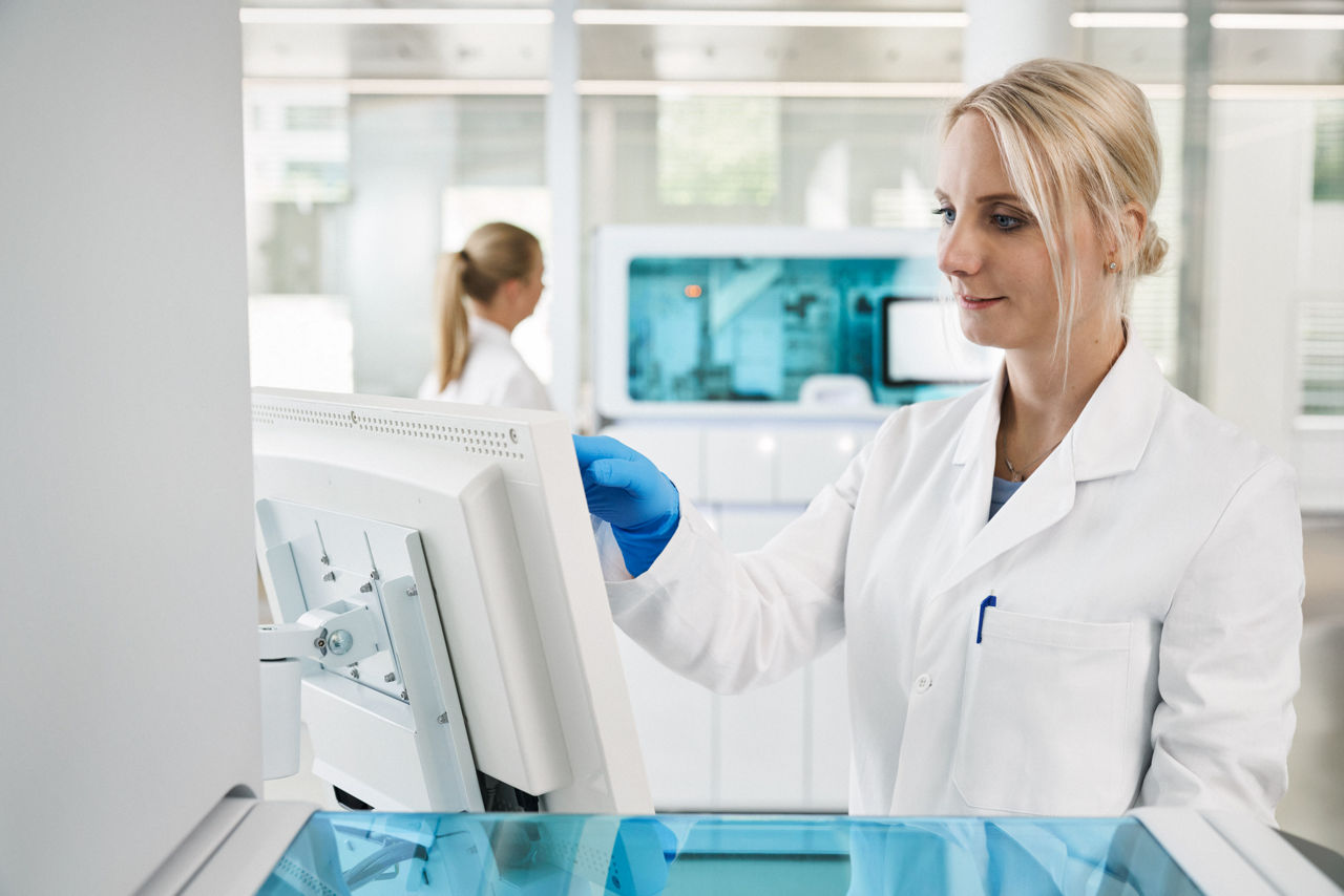 Two lab technicians in a molecular lab In the forefront a technician is using the screen connected to a cobas analyzer