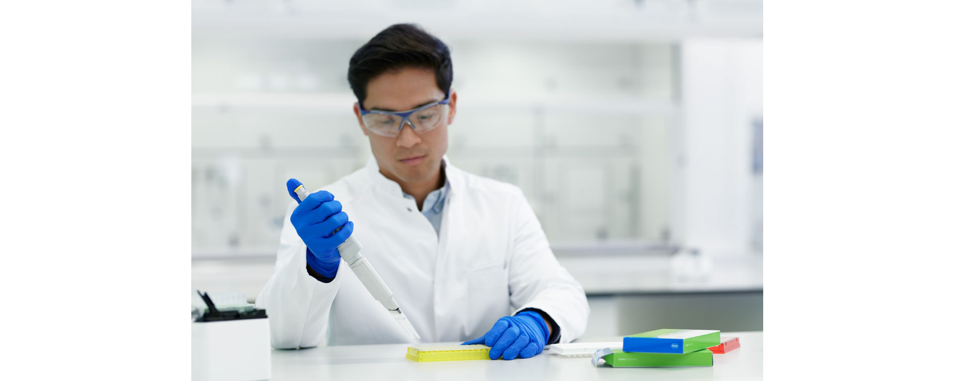 A lab technician carefully uses a pipette to add reagents from an NGS library preparation for sequencing kit to a vial