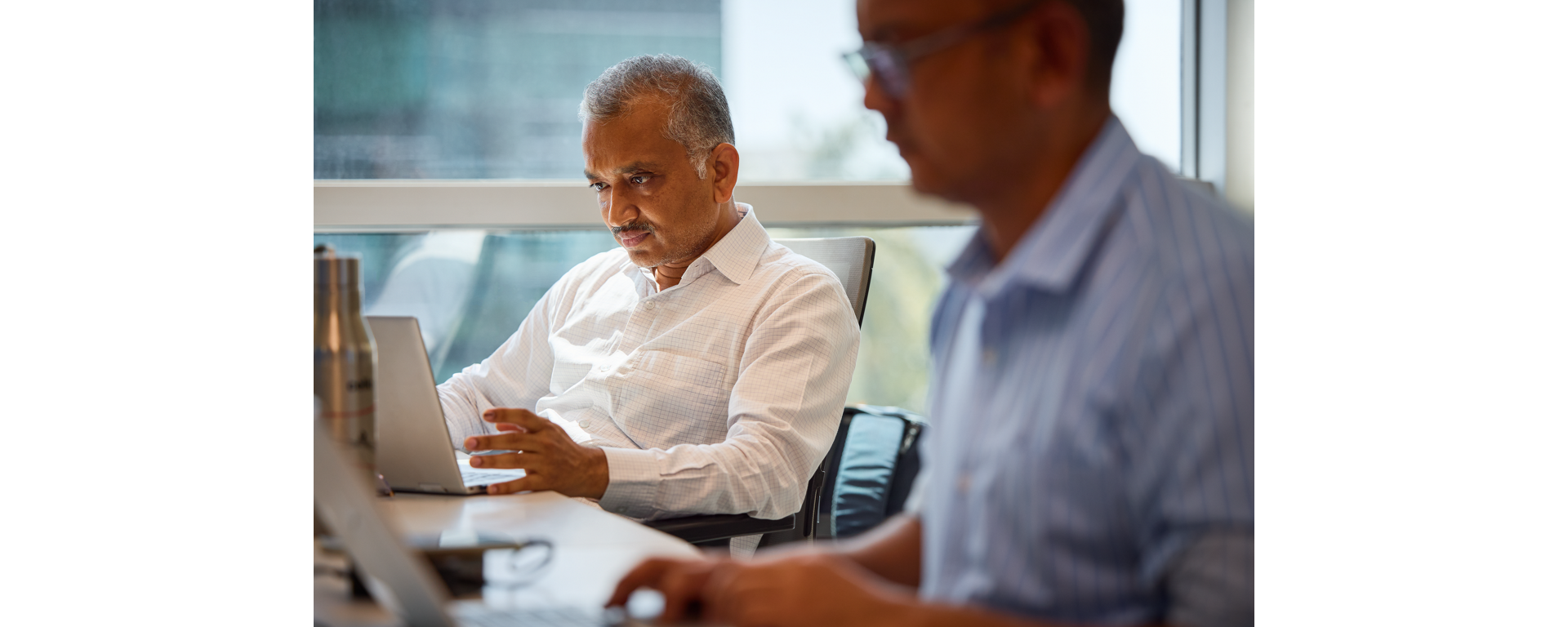 Two researchers looking at NGS data analysis results on laptop computers  in an office