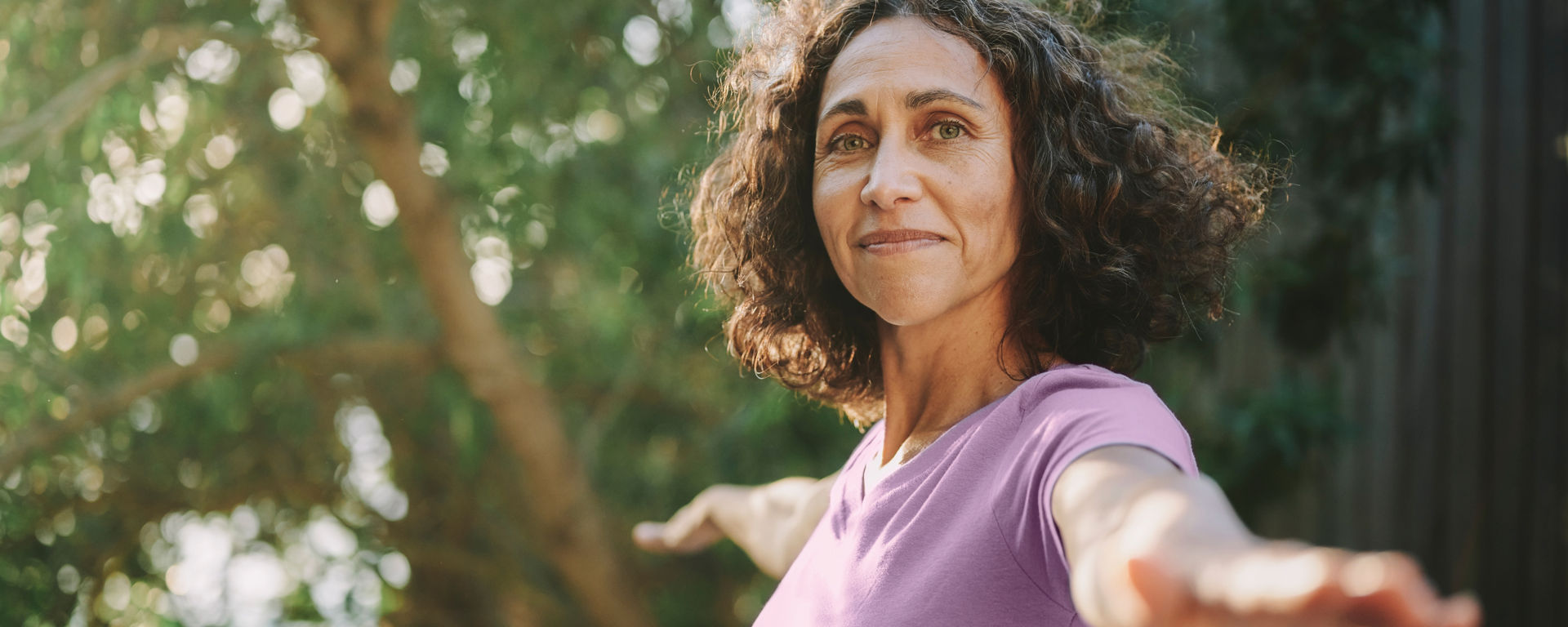 Portrait of a smiling mature woman practicing yoga outside in a park in the summertime