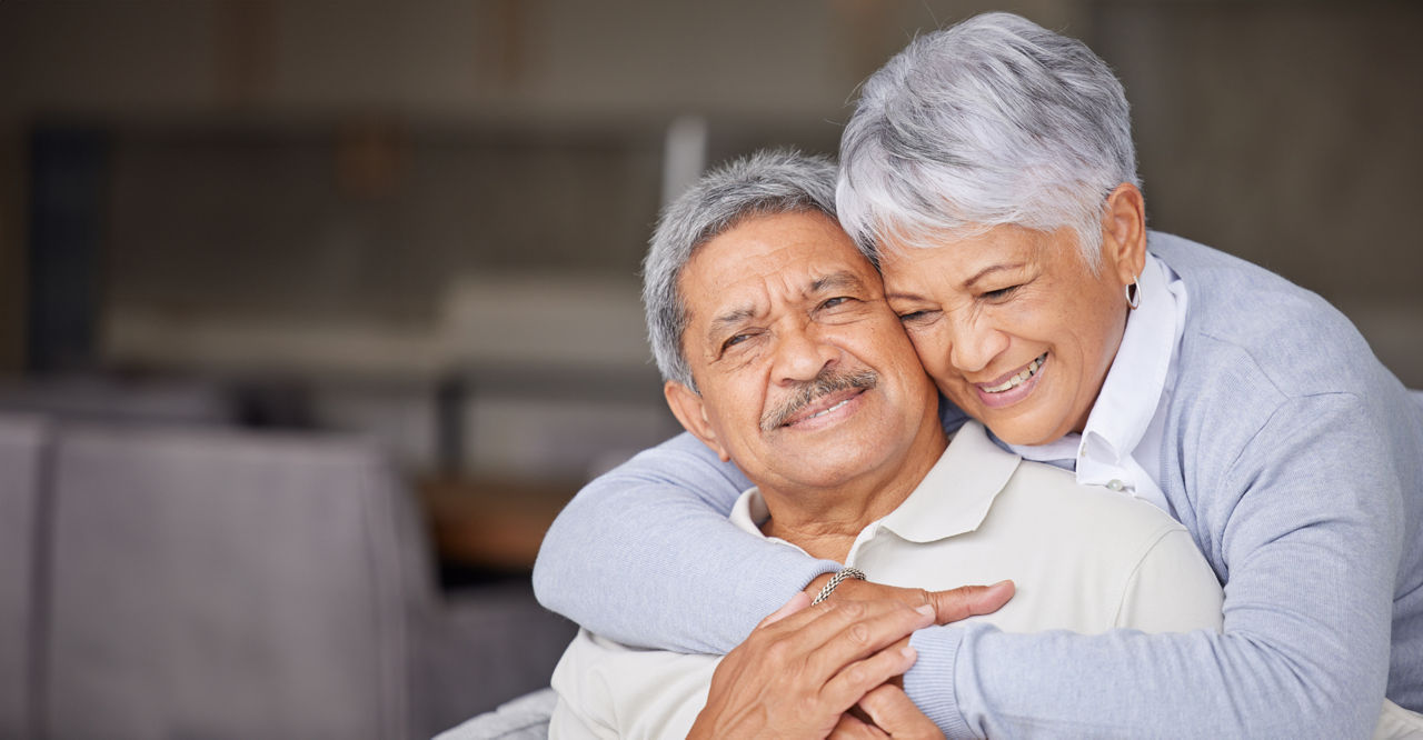 A gray-haired man and a woman hugging each other and smiling