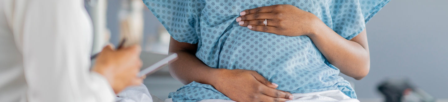 a pregnant woman in hospital room speaking with doctor 