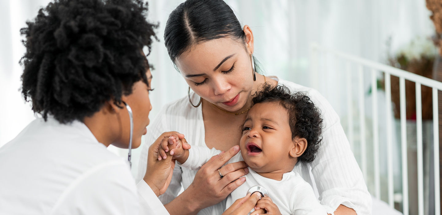 doctor examining baby with mother