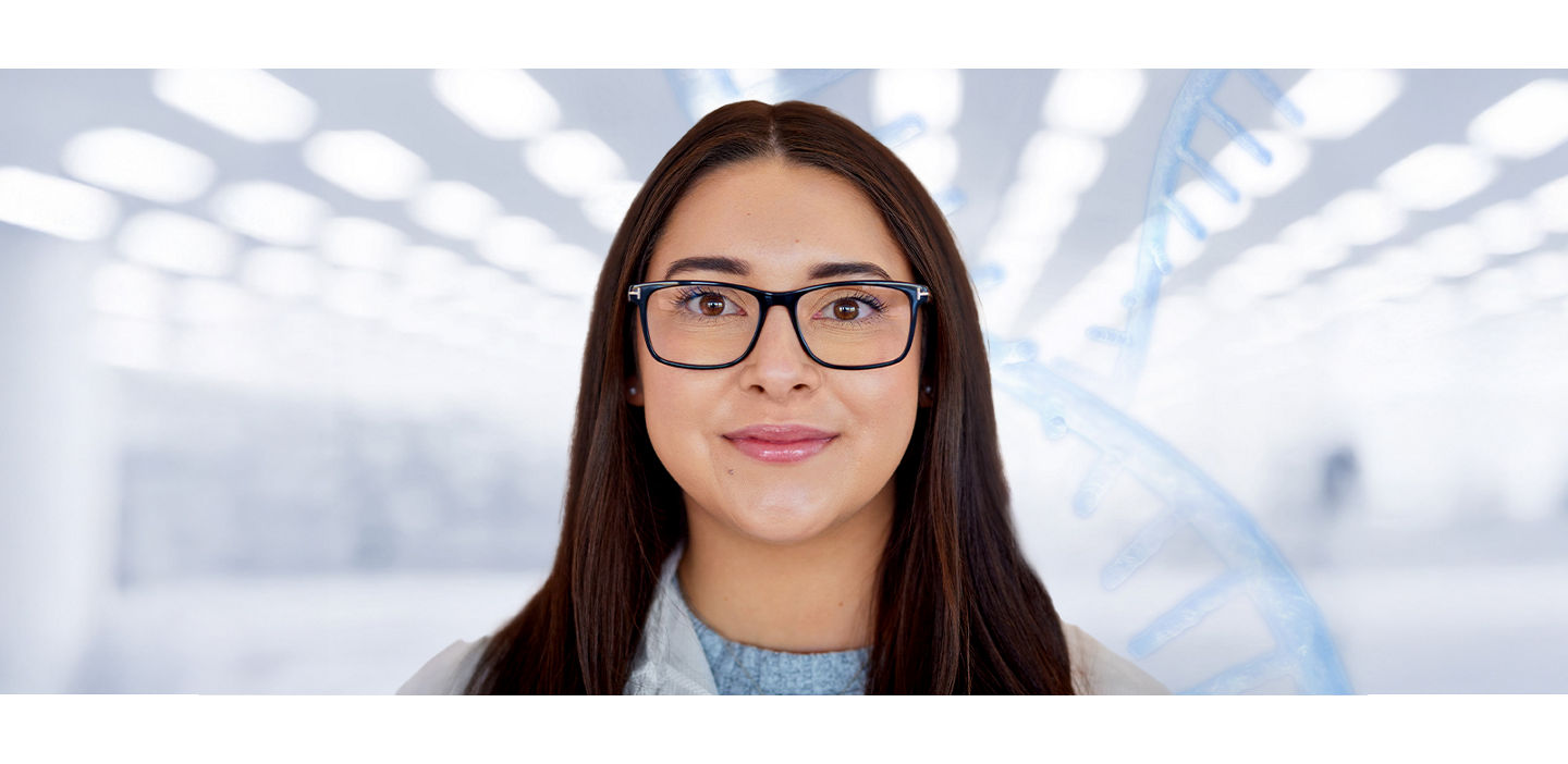 A woman wearing glasses in a laboratory looks determinedly at the camera