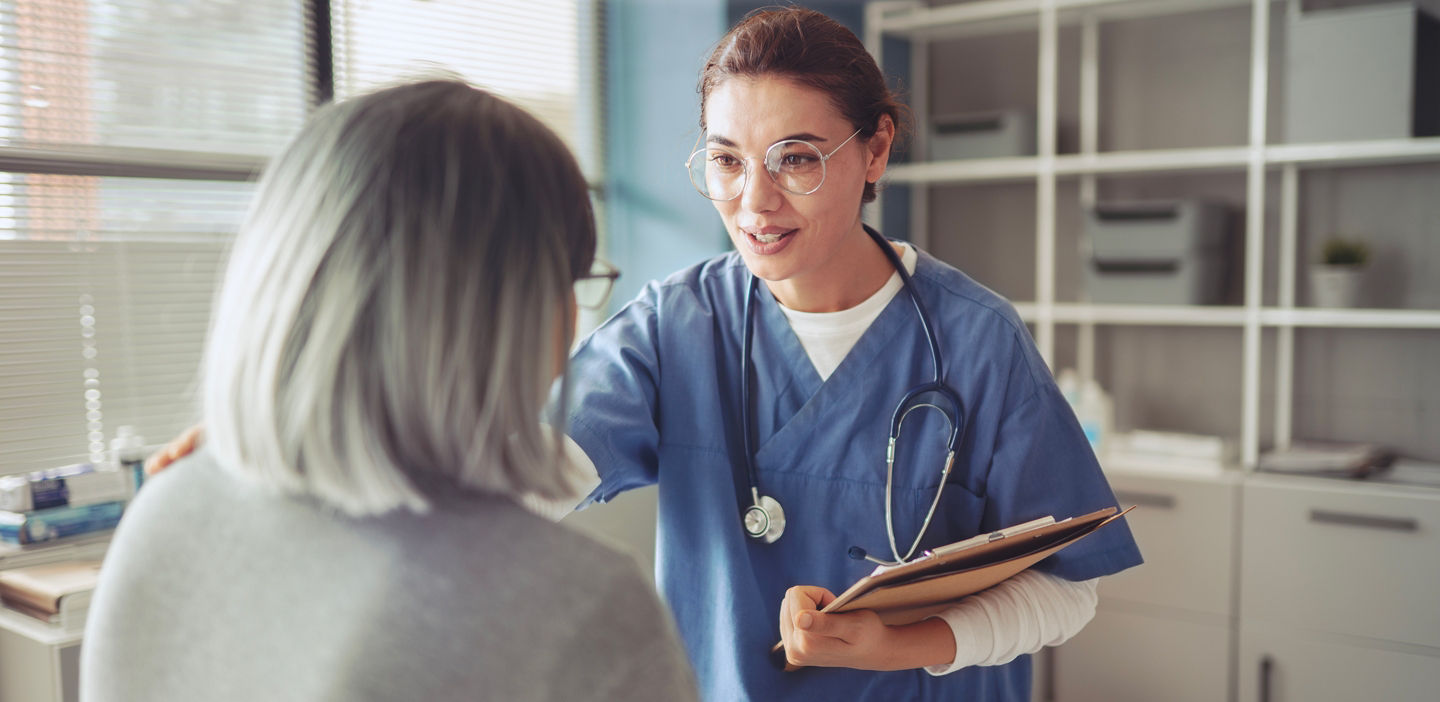 older female patient speaking with female doctor in clinic