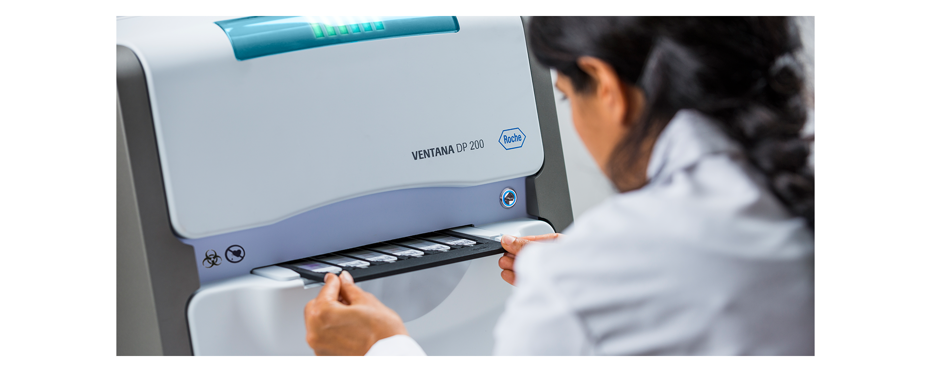 A pathologist pulling out The VENTANA DP 200 digital pathology slide scanner tray